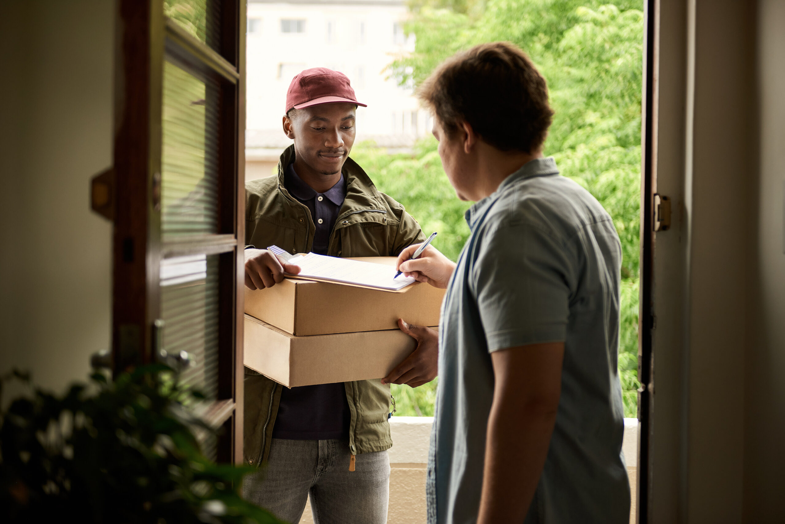 Man Signing For A Courier Package At His Front Door